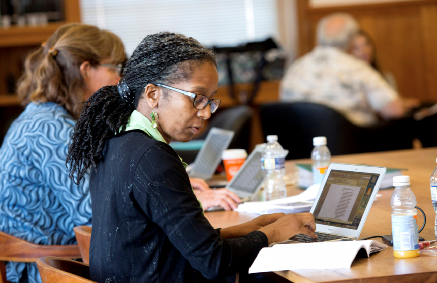 A professor sitting at a desk, writing on a computer