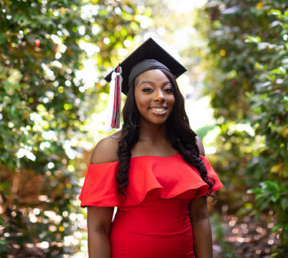 Danielle Obiri poses in a red dress with her graduation cap