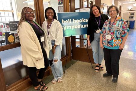 Panelists stand next to bell hooks center sign