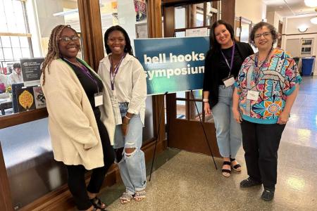 Panelists stand next to bell hooks center sign