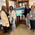 Panelists stand next to bell hooks center sign